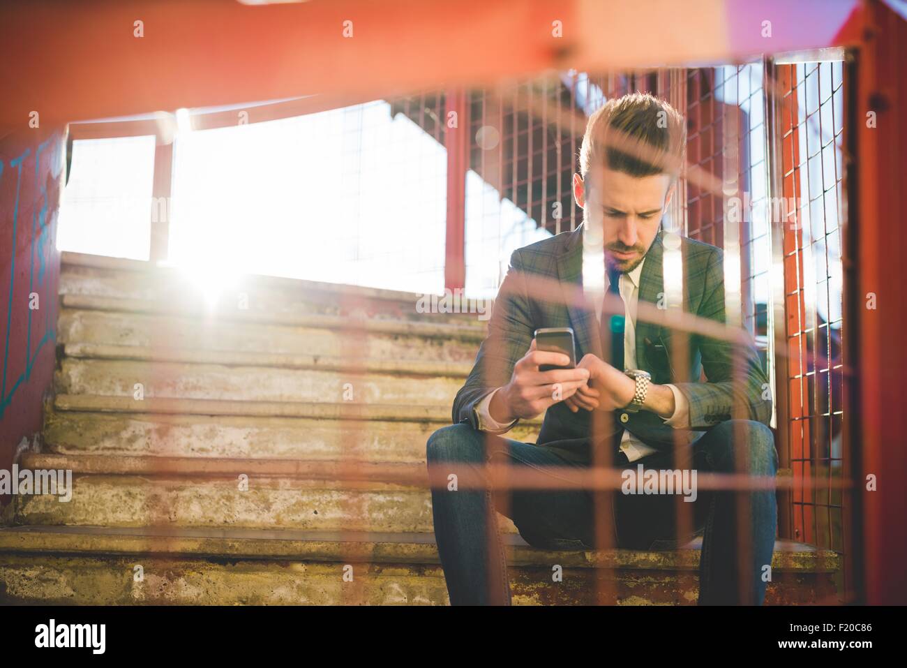 Stilvolle junger Mann mit Smartphone überprüfen der Zeit am Steg Stockfoto