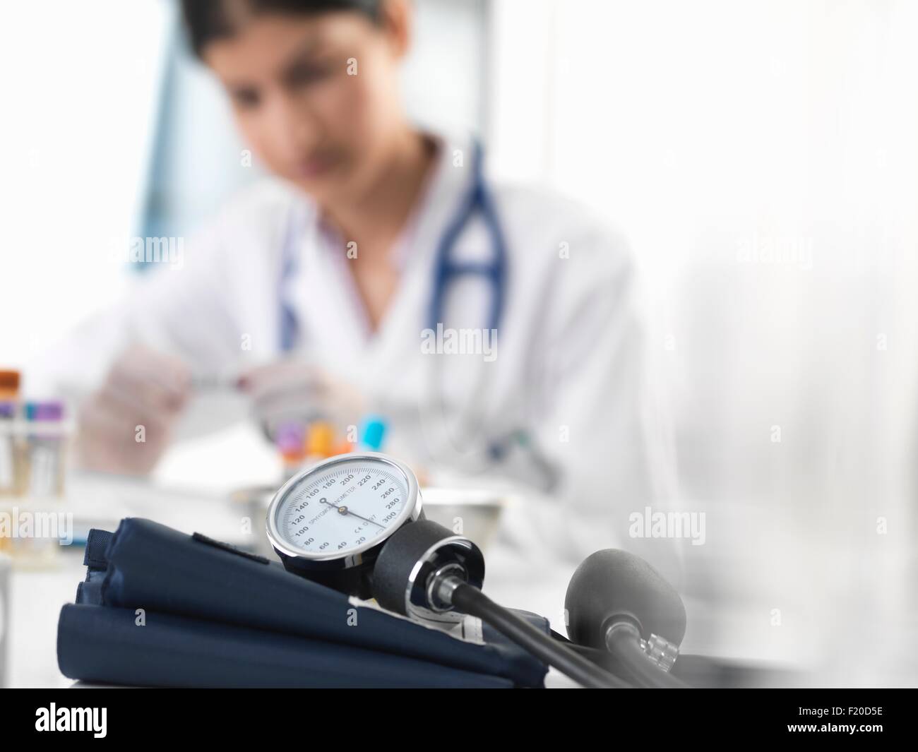 Ärztin untersucht Reagenzglas Probe am Schreibtisch in Klinik Stockfoto