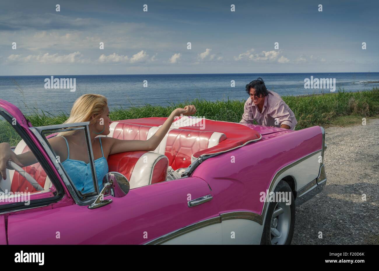 Junger Mann schob rosa Oldtimer Cabrio an Küste, während Freundin, Havanna, Kuba treibt Stockfoto