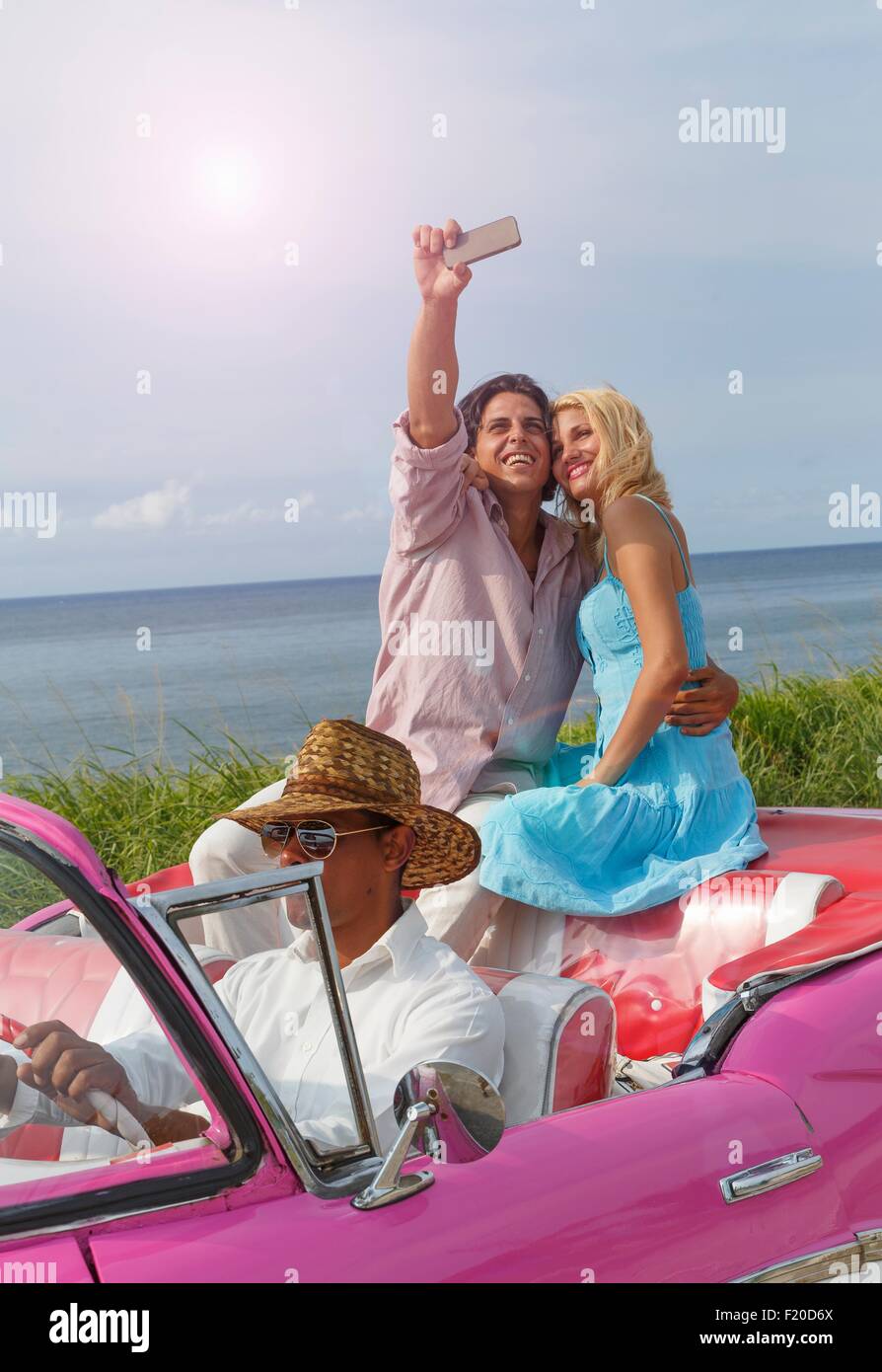 Junges Paar unter Smartphone Selfie Oldtimer Cabrio, Havanna, Kuba Stockfoto