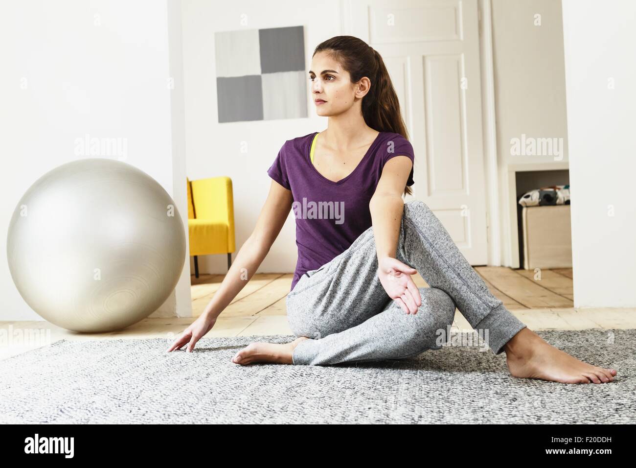 Junge Frau praktizieren Yoga am Boden des Wohnzimmers Stockfoto