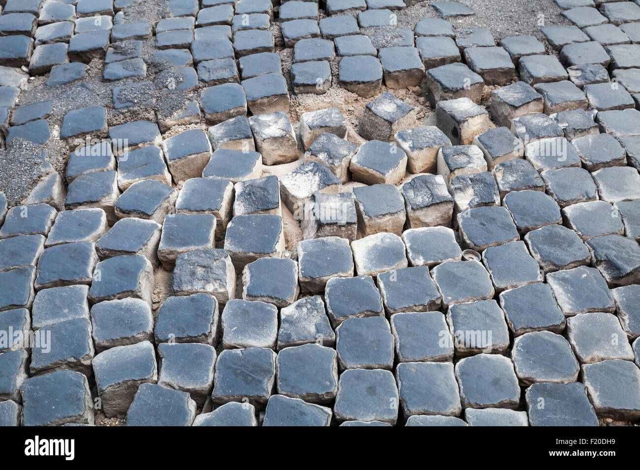 Beschädigte Straße Kopfsteinpflaster mit Sand im Hintergrund Stockfoto