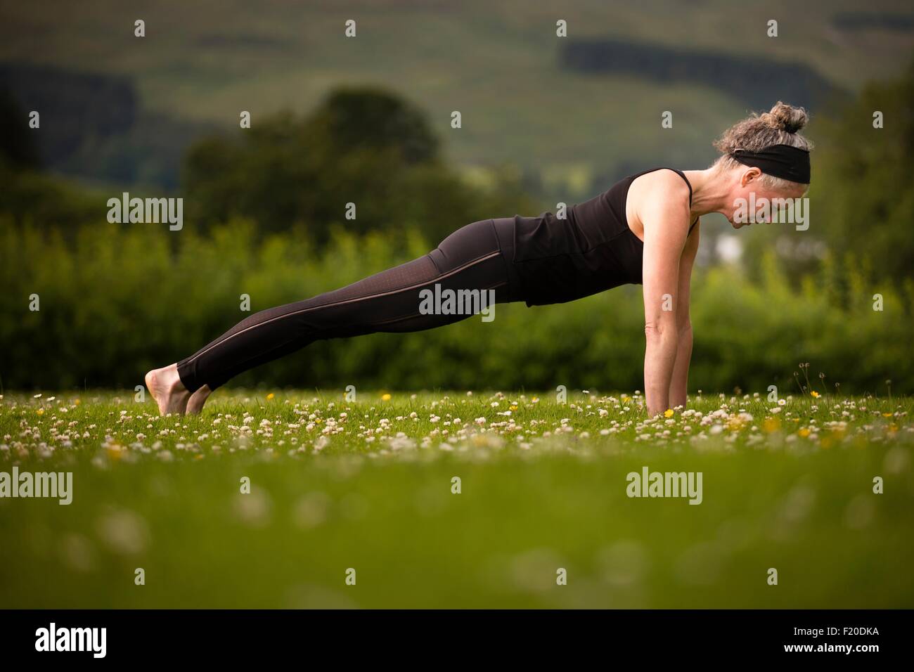 Reife Frau praktizieren Yoga Plank im Feld Stockfoto