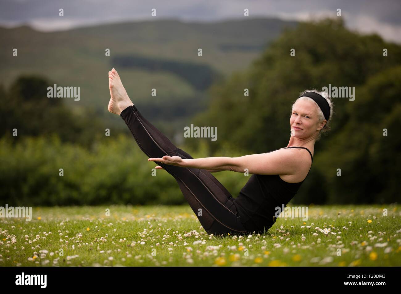 Reife Frau praktizieren Yoga-Boot-Pose im Feld Stockfoto