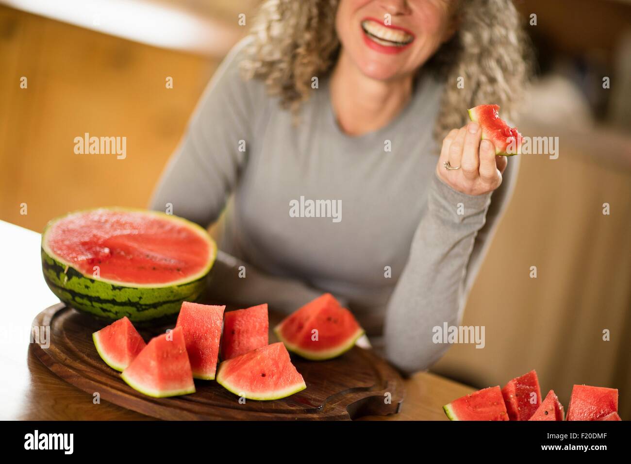 Reife Frau Essen Wassermelone in Küche Stockfoto