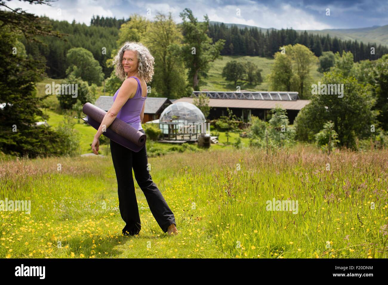 Porträt von Reife Frau, die Yoga-Matte im Bereich Eco Lodge Stockfoto