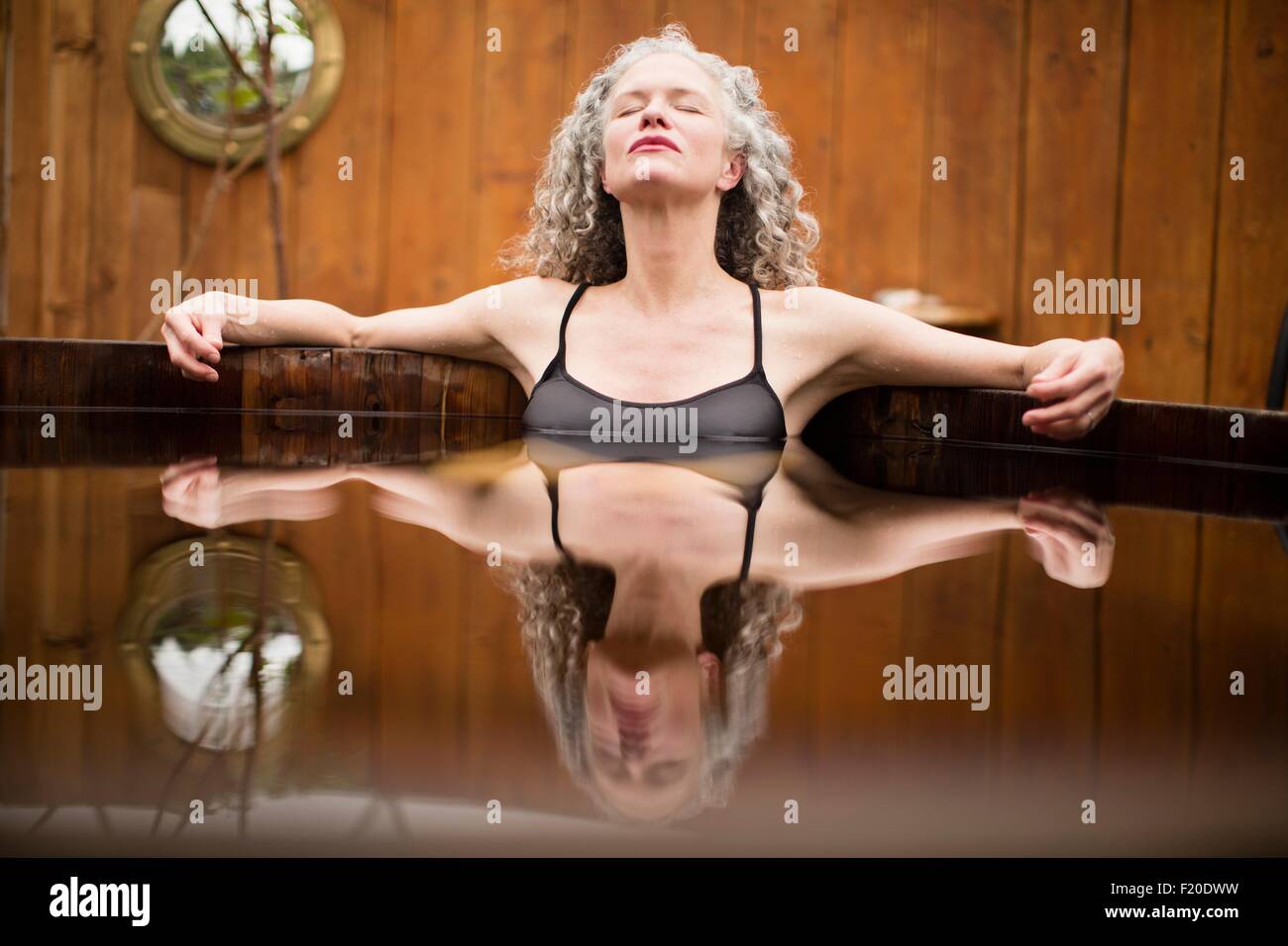 Reife Frau mit geschlossenen Augen in Whirlpool Eco Retreat Meditation Stockfoto