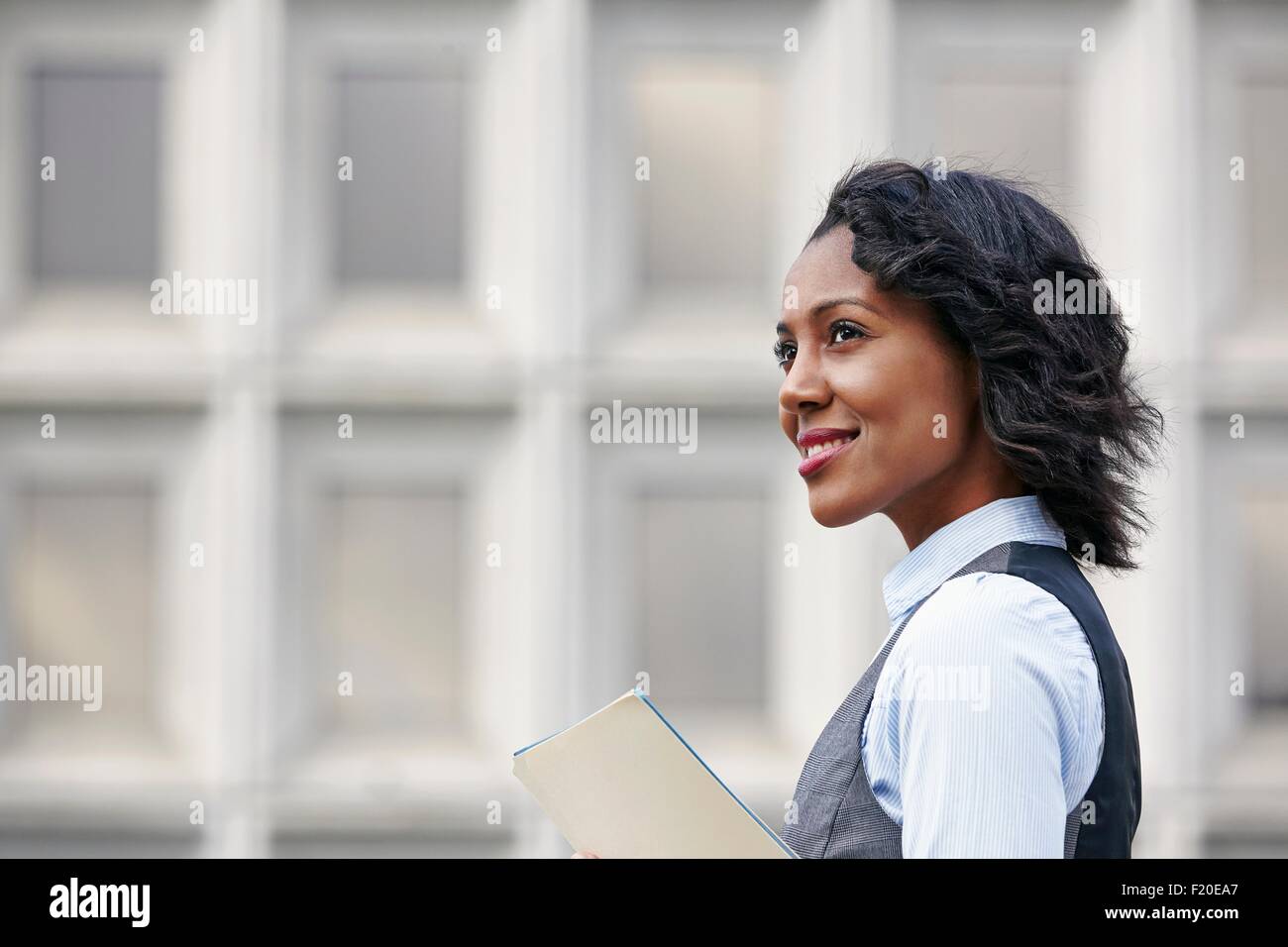 Porträt des jungen Geschäftsfrau mit Papier arbeiten, schauen Weg, lächelnd, Seitenansicht Stockfoto