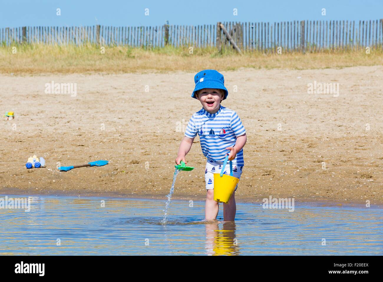 Porträt des kleinen Jungen sammeln Meerwasser in Spielzeug Eimer am Strand, Marennes, Charente-Maritime, Frankreich Stockfoto