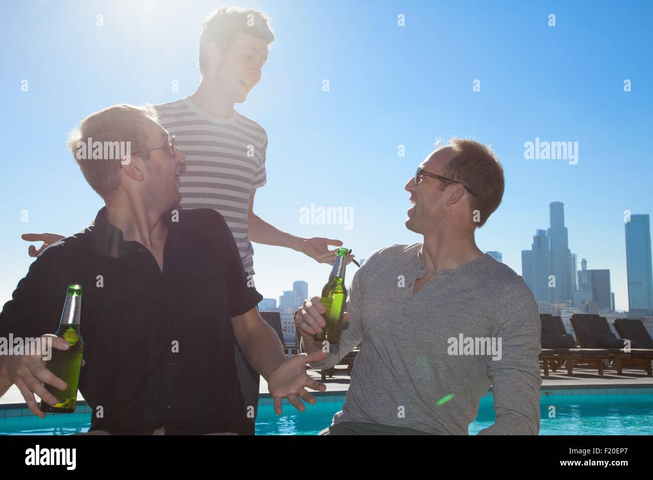 Drei erwachsenen männlichen Freunden trinken Bier an der Bar auf der Dachterrasse mit Skyline von Los Angeles, USA Stockfoto