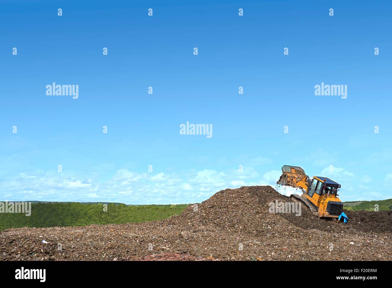 Digger auf Hügel vergraben Abfall auf der Deponie Stockfoto