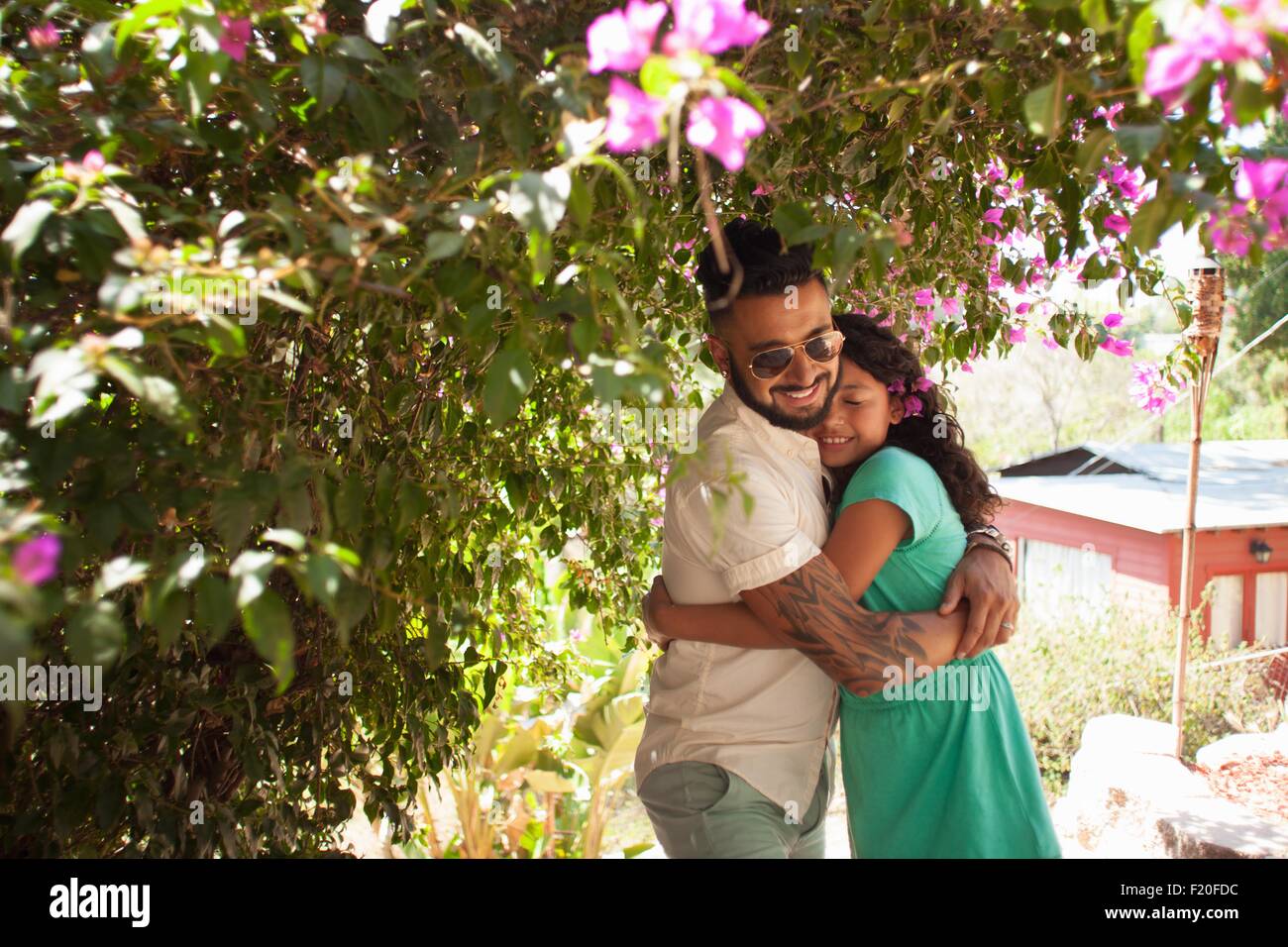 Mitte erwachsener Mann umarmt Tochter im Garten Stockfoto