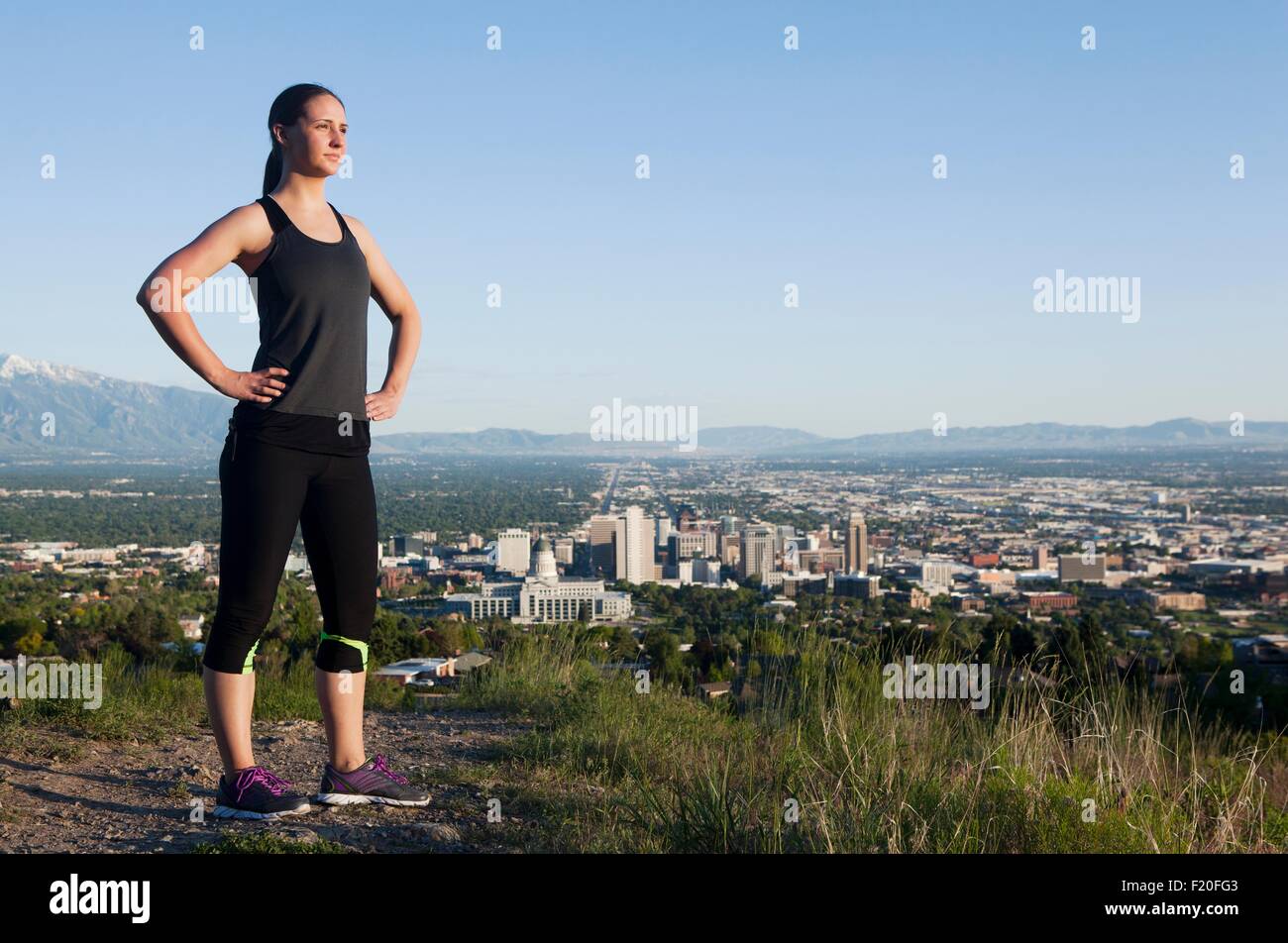 Porträt der jungen weiblichen Läufer auf Feldweg oberhalb der Stadt im Tal Stockfoto