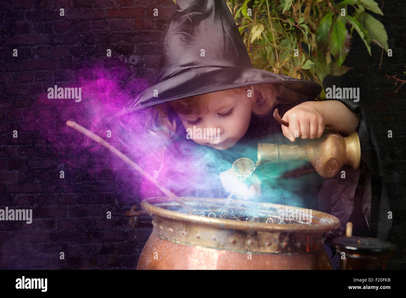 kleine Halloween Hexe mit Kessel, im freien Stockfoto