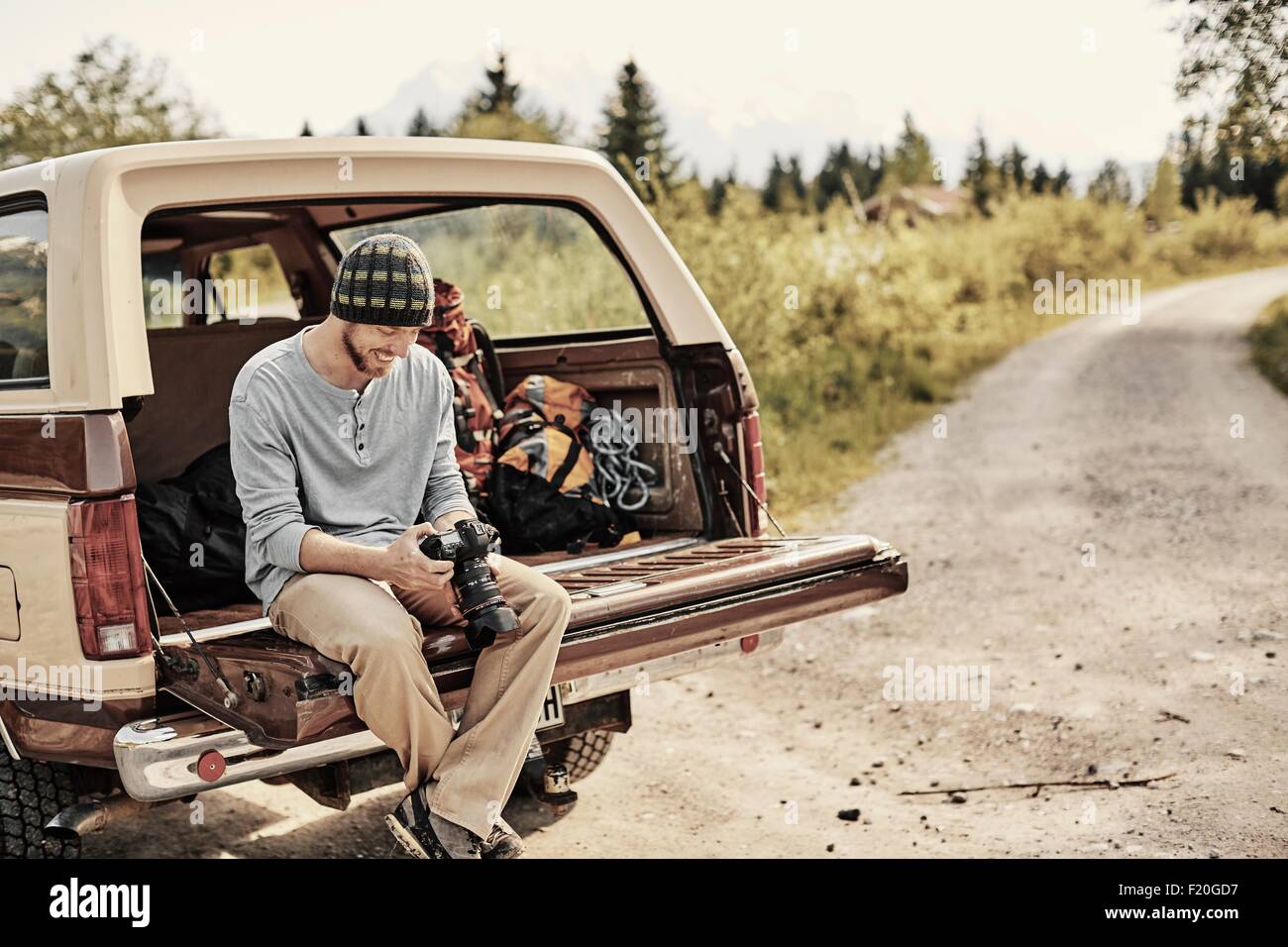 Junger Mann sitzen auf Rückseite des Pickup-Truck, die Kamera zu halten Stockfoto