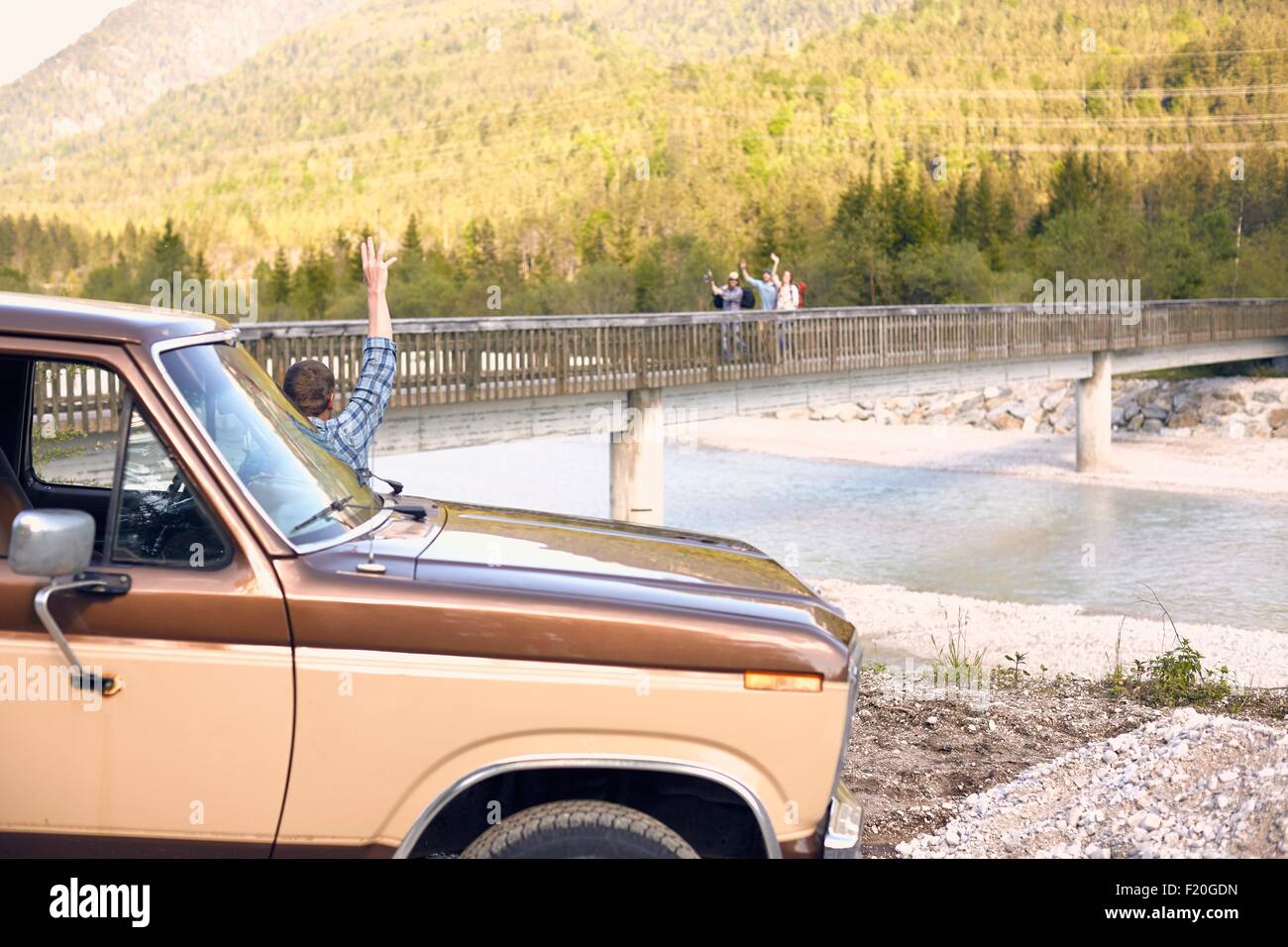 Mann, der mit einem Fahrzeug winken Menschen auf der Brücke im Hintergrund Stockfoto
