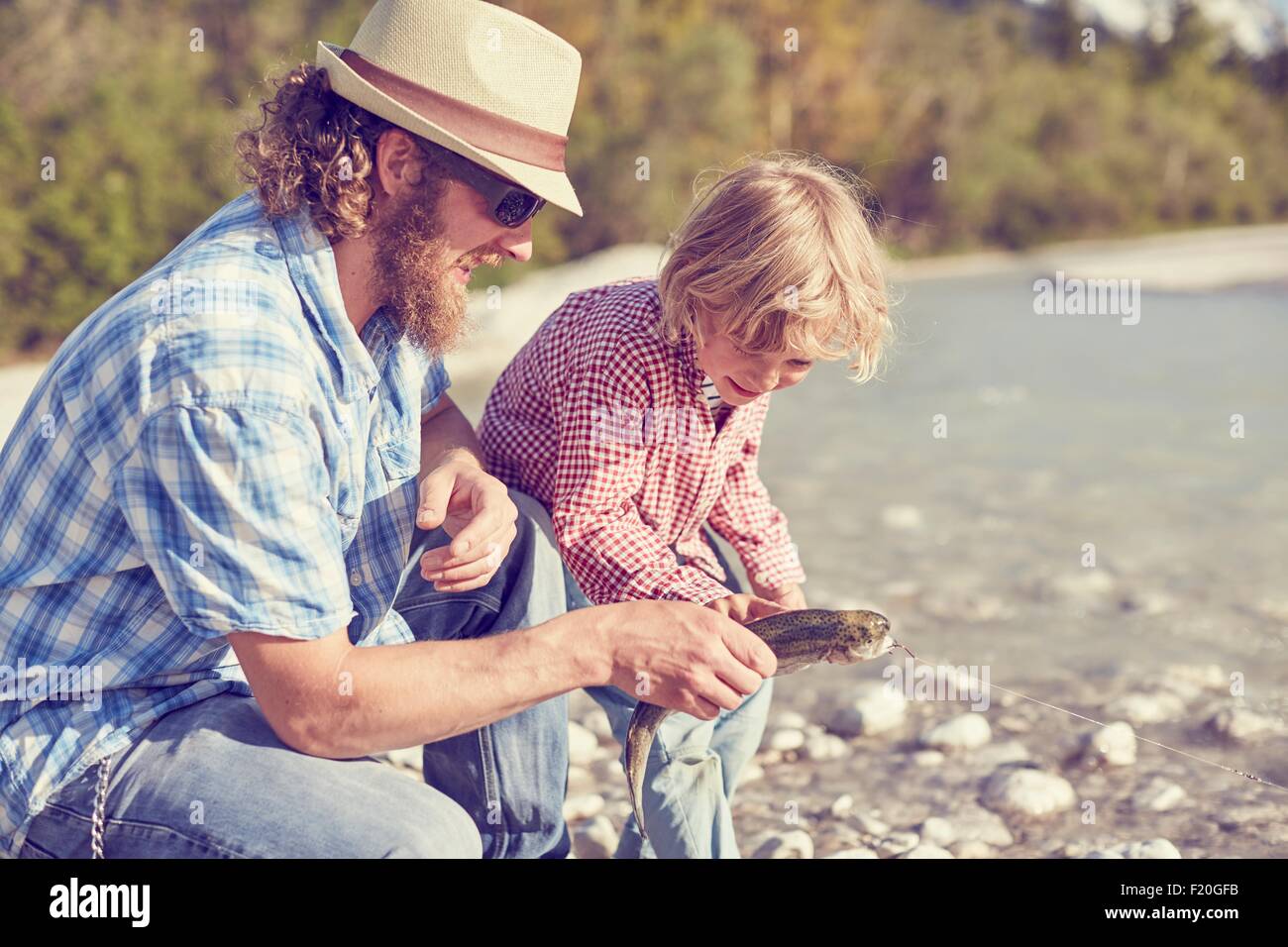 Mitte erwachsenen Mann und der junge neben Fluss Prüfung Fisch an Angelschnur befestigt Stockfoto