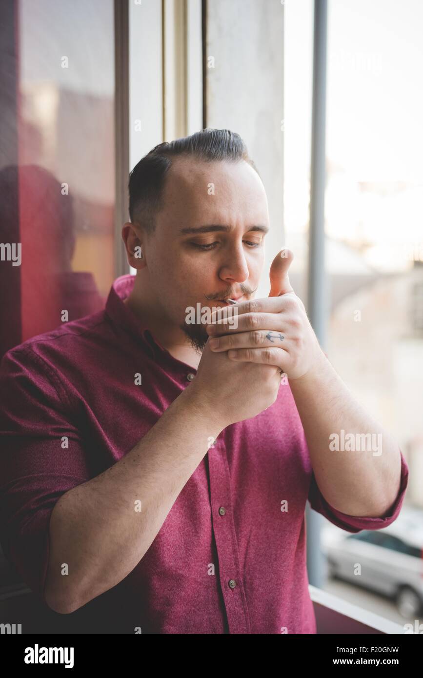 Porträt des jungen Mannes Fenster Rauchen Stockfoto