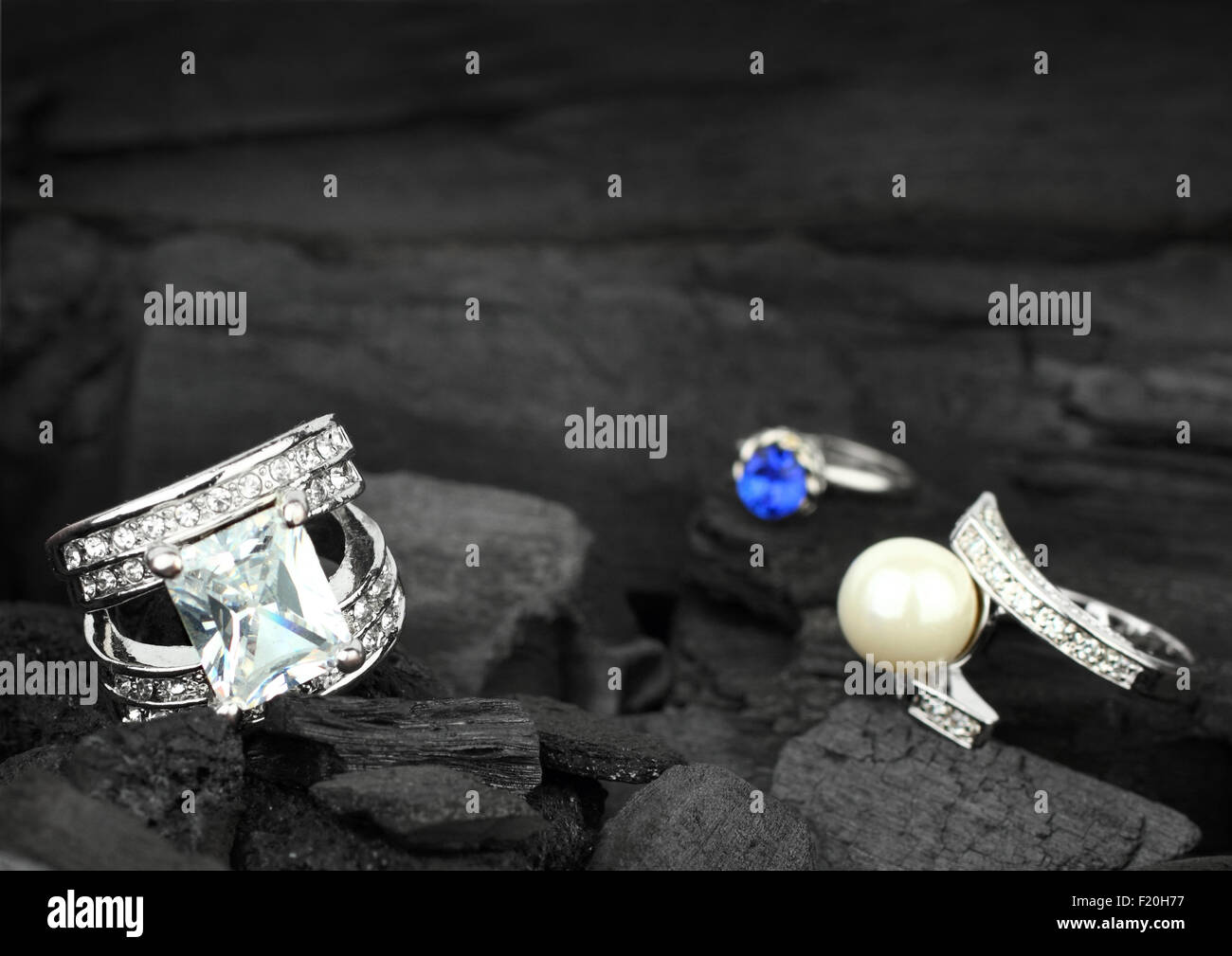 Paar Schmuck Ringe mit brillanten, Edelsteine und Perlen auf Steinkohle Hintergrund, soft-Fokus Stockfoto
