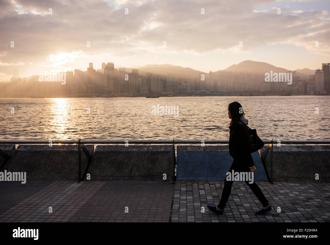 Seitenansicht der jungen Frau zu Fuß vorbei an Wasser, Hong Kong, China Stockfoto