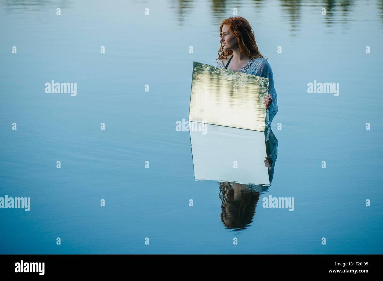 Junge Frau im See, Holding-Spiegel, Wasser plätschert in Spiegel reflektieren Stockfoto