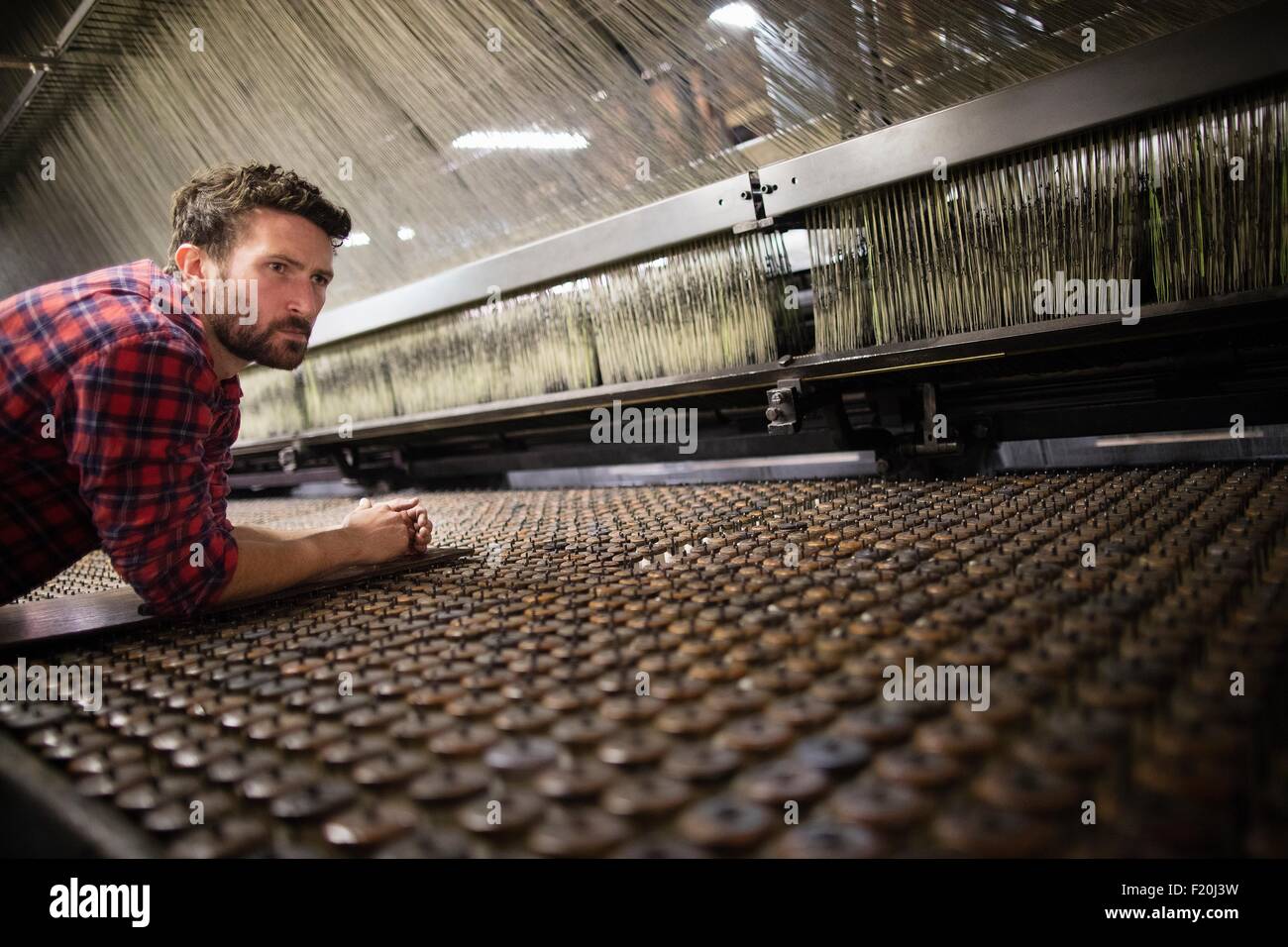 Männliche Weber Überwachung alten Webmaschine in Textilfabrik Stockfoto