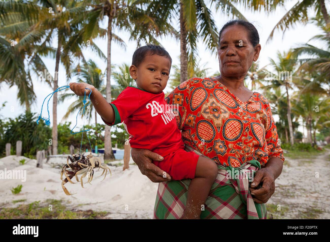 Indonesien, Maluku Provinz, East Seram, Grogos Island, Grand-Mutter mit ihrem Enkel mit Krabben für die Wiedergabe von Stockfoto