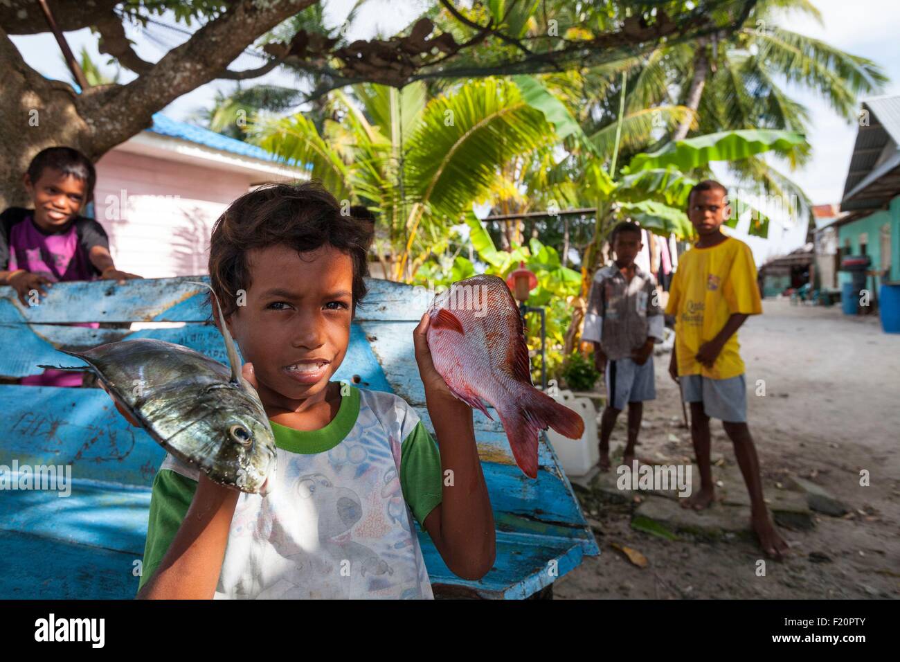 Indonesien, Maluku Provinz, East Seram, Grogos Island, Kind zeigt Fische Stockfoto