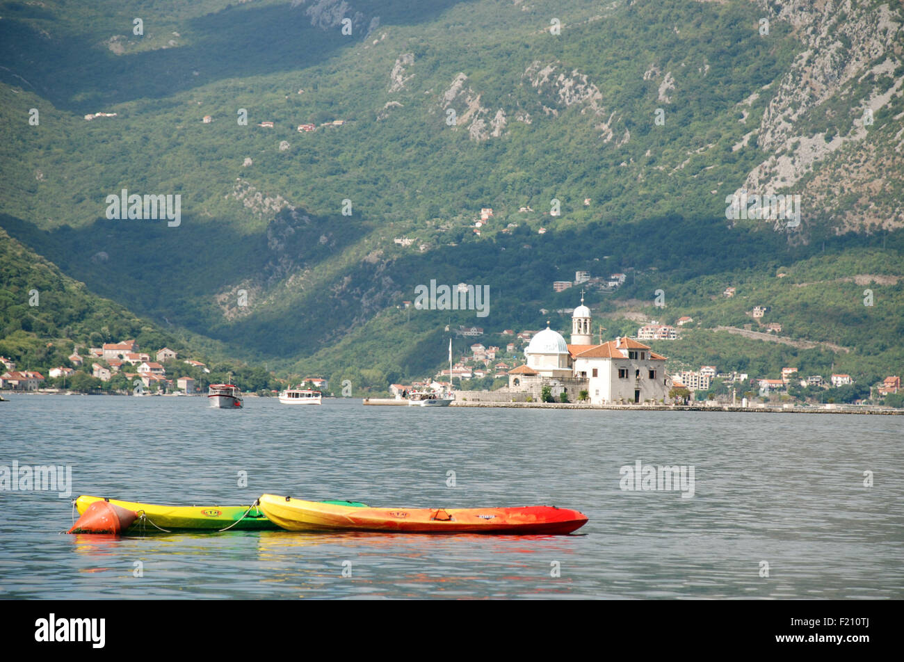 die Insel der Dame der Felsen in der Bucht von Kotor mit Kalksteinberge im Hintergrund mit Booten im Vordergrund Stockfoto