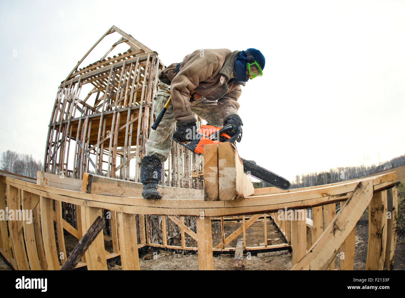 zerschnitten Sie Arbeiter mit benzinbetriebenen sah, hölzerne Ziegel auf den Aufbau der Website Holzhaus Stockfoto