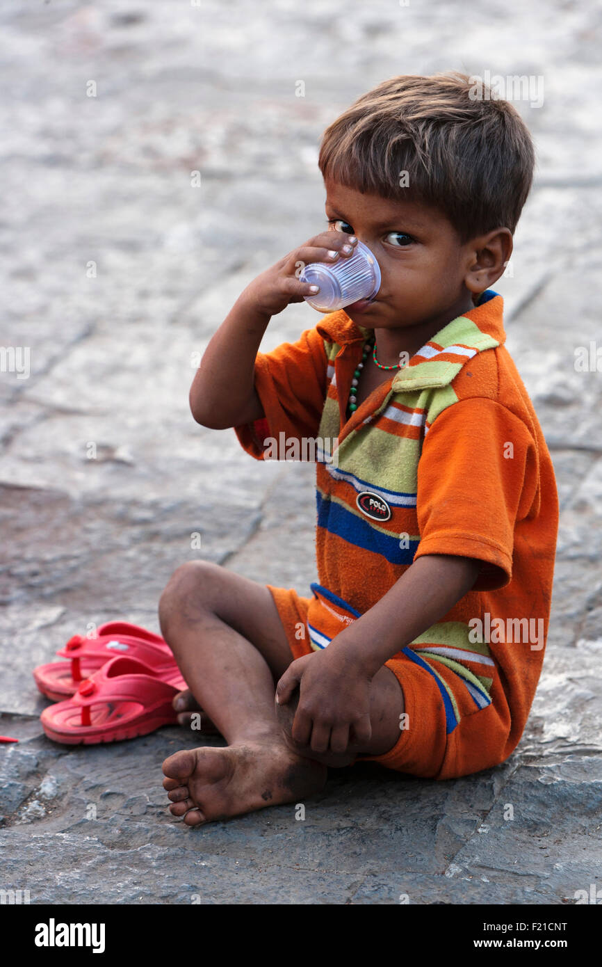 Indien, Maharashtra, Mumbai, jungen trinken Tee aus einem Plastikbecher beim Sitzen auf einem Pflaster. Stockfoto