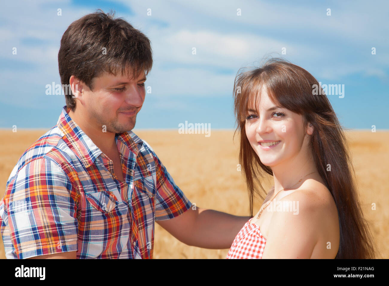 Porträt eines jungen Paares auf dem Hintergrund von einem Weizenfeld an einem sonnigen Tag Stockfoto