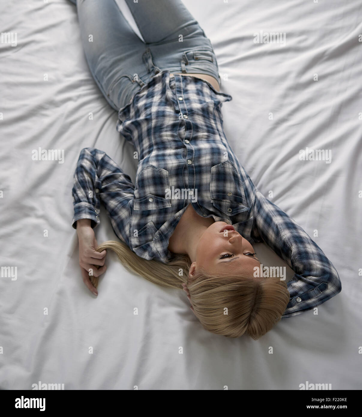 Nachdenkliche junge Frau liegt auf dem Bett, traurige Gefühle Stockfoto