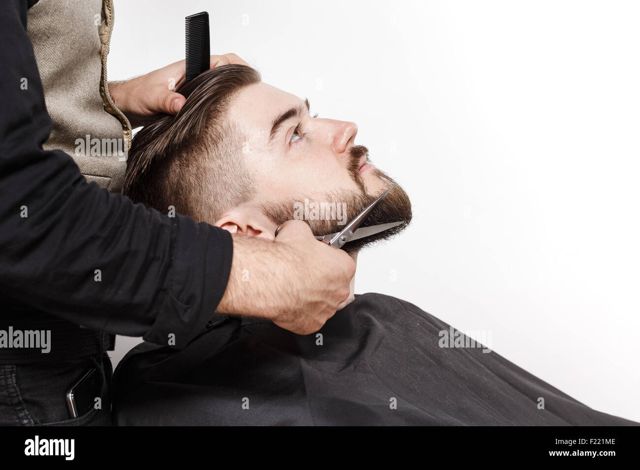 Barber, in schwarzes Hemd tragen einen Bart von brutalen Jüngling mit  schwarzen Kamm und Schere, schneiden, auf weißem Hintergrund im studio  Stockfotografie - Alamy