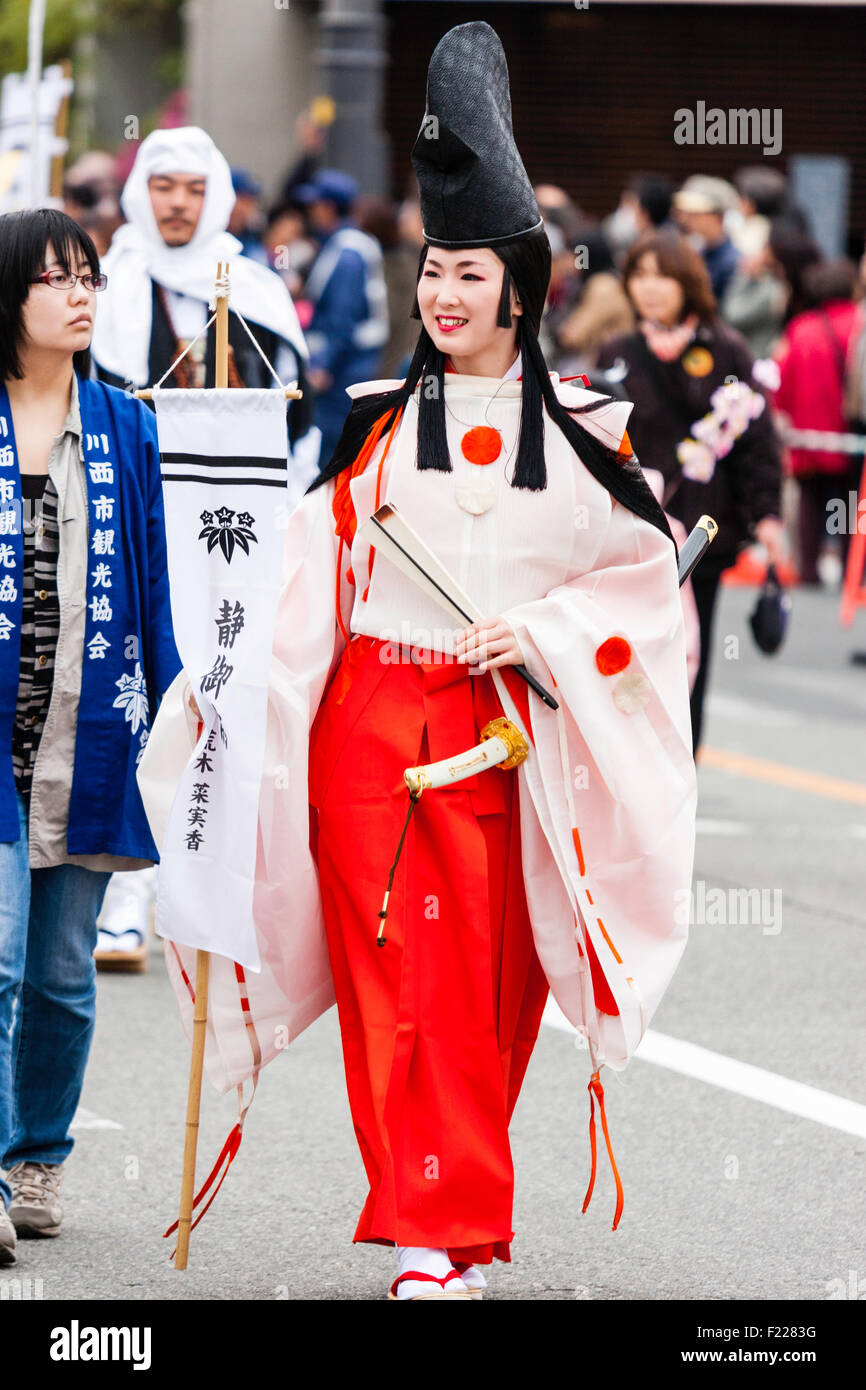 Genji Festival Parade in Tada, Japan. Junge Frau gekleidet wie Heian shirabyoshi Tänzer, mit langen roten Rock, weiße Bluse, und hohen schwarzen Hut. Lächelnd. Stockfoto