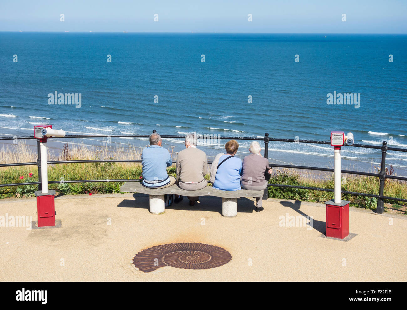 Zwei älteres Ehepaar sitzt auf der Bank mit Blick auf Meer Fron oben die promenade am Saltburn am Meer, North Yorkshire, UK. Stockfoto