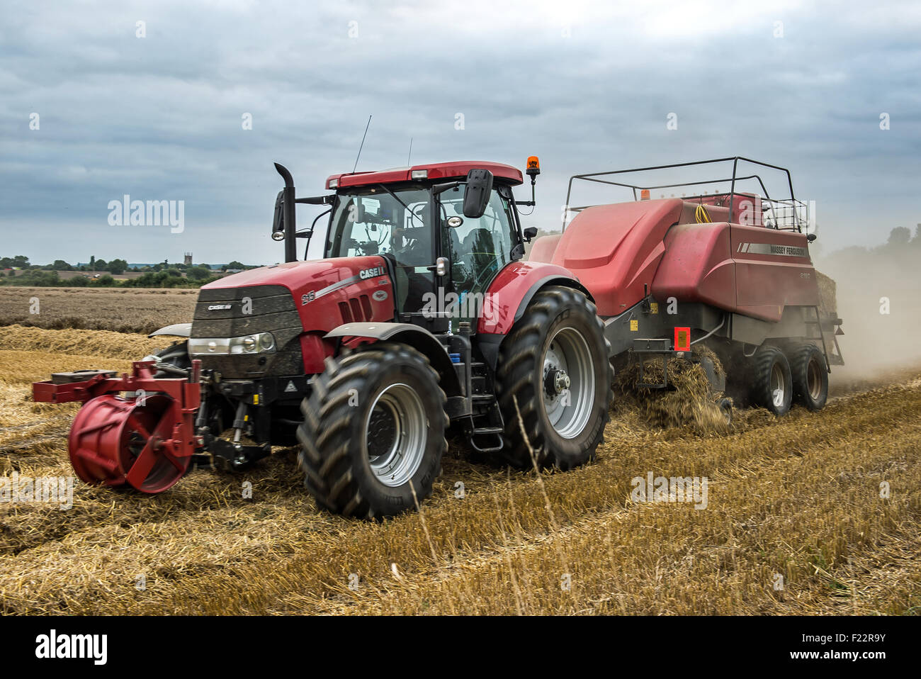 Ein Traktor und Bailer Abholung und Rettungsplan für das Stroh bilden das Weizenfeld. Stockfoto