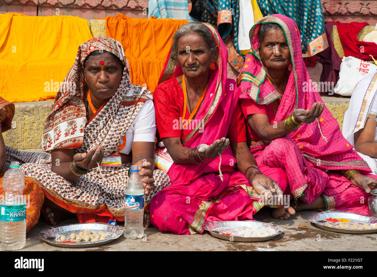 Pilger durchhalten Palmen, während sie darauf warten, Prasad (Lebensmittel als religiöse Opfergabe) auf den Ghats neben den Ganges in Varanasi zu erhalten Stockfoto