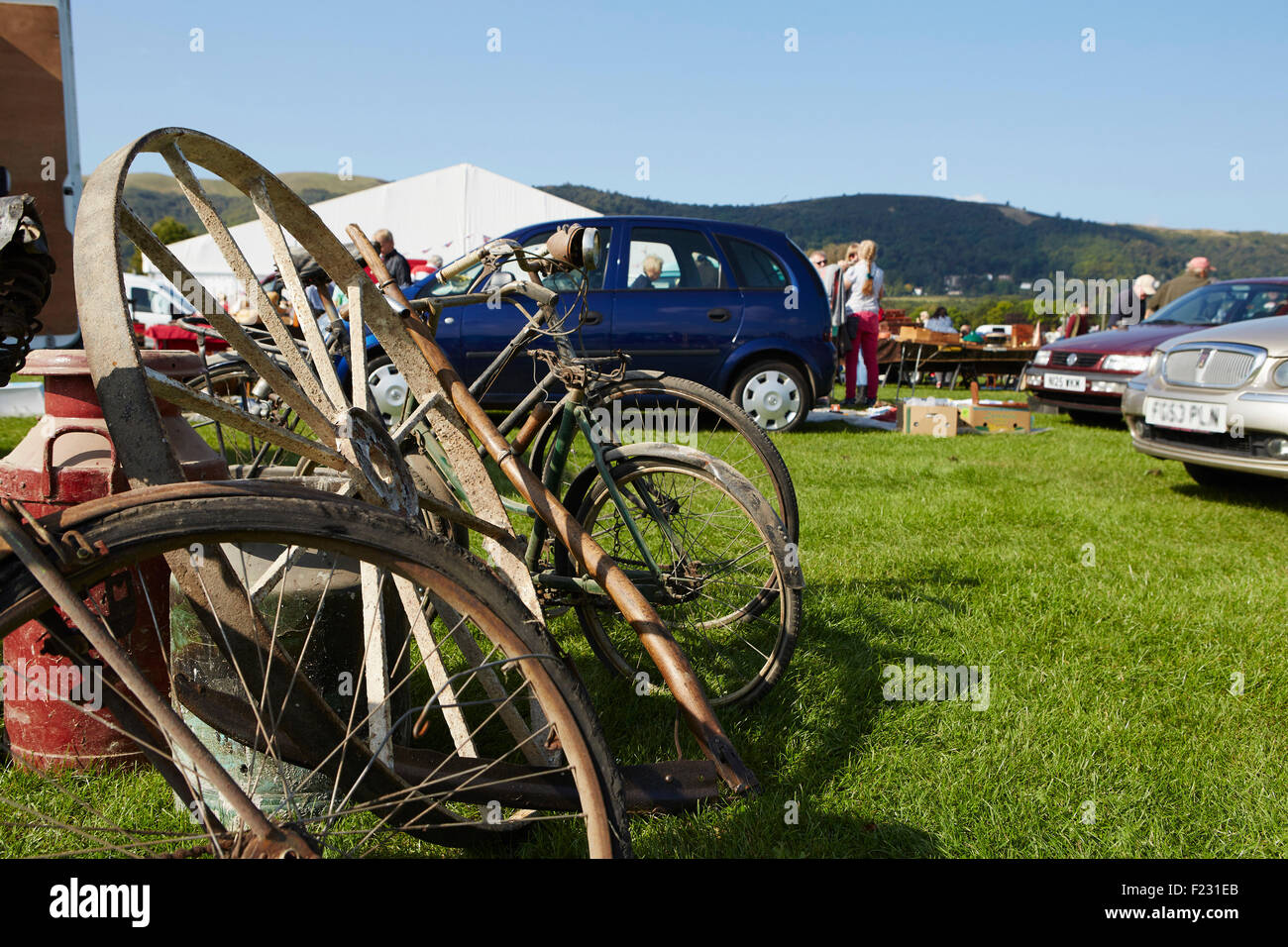 Auswahl an Vintage Fahrräder, Felge und eine alte Milchkanne für Verkauf auf einem Flohmarkt-Event. Stockfoto