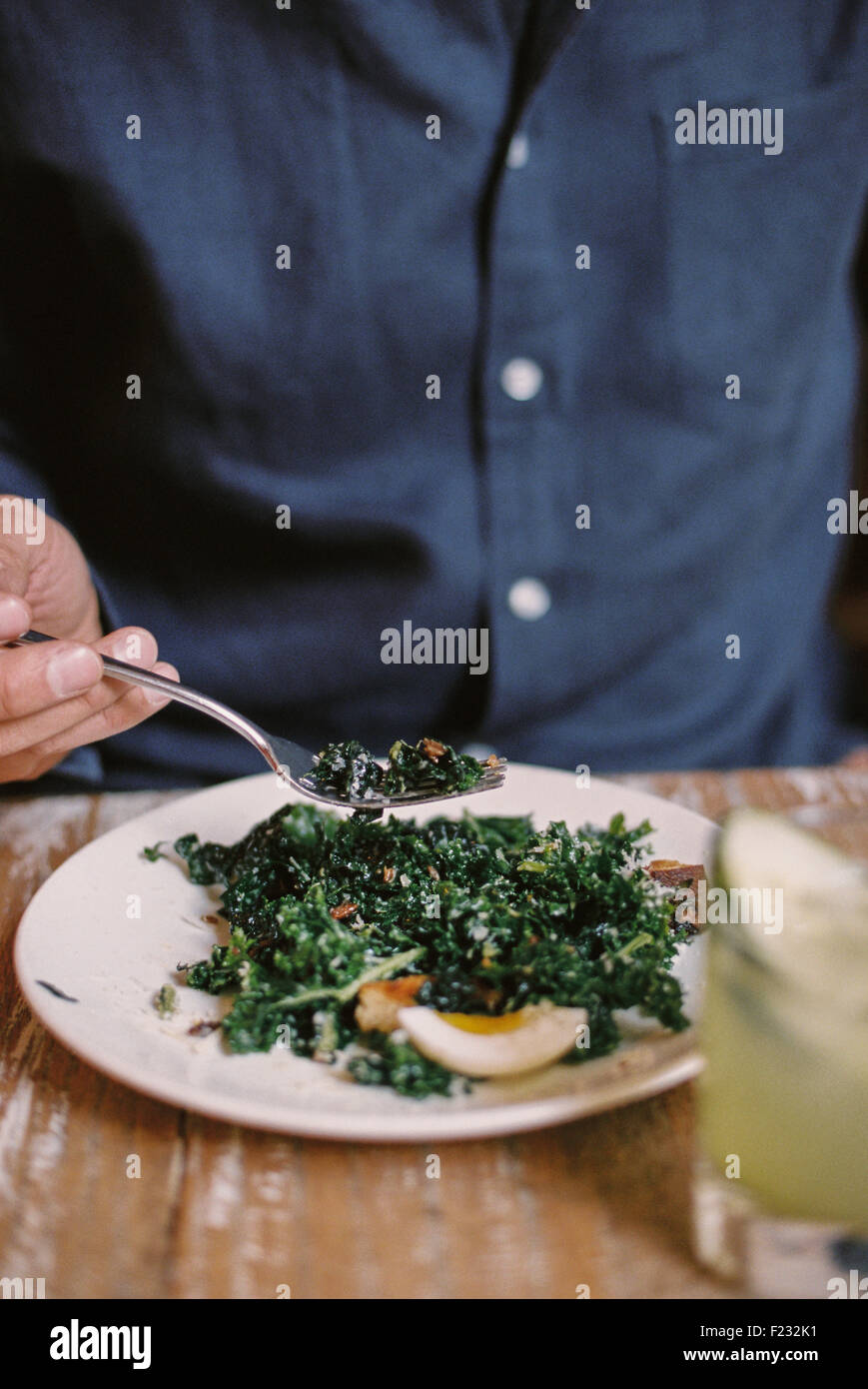 Eine Person sitzt ein Essen an einem Tisch mit einer Gabel einstechen. Stockfoto