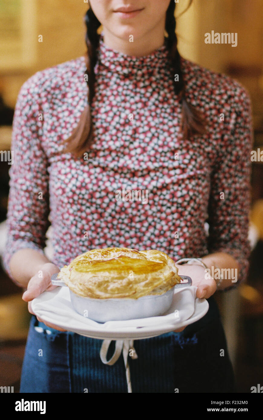 Eine Frau, die ein frisches gebackenes Gebäck gekrönt Kuchen auf einen Teller. Stockfoto