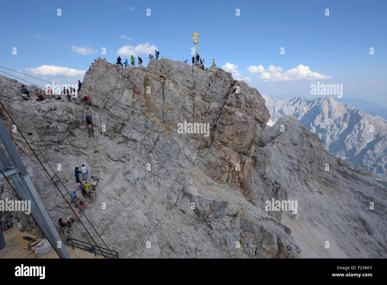 Gipfel von Deutschlands höchster Berg Zugspitze mit dem goldenen Gipfel überqueren und überfüllt mit Menschen, Deutschland Stockfoto