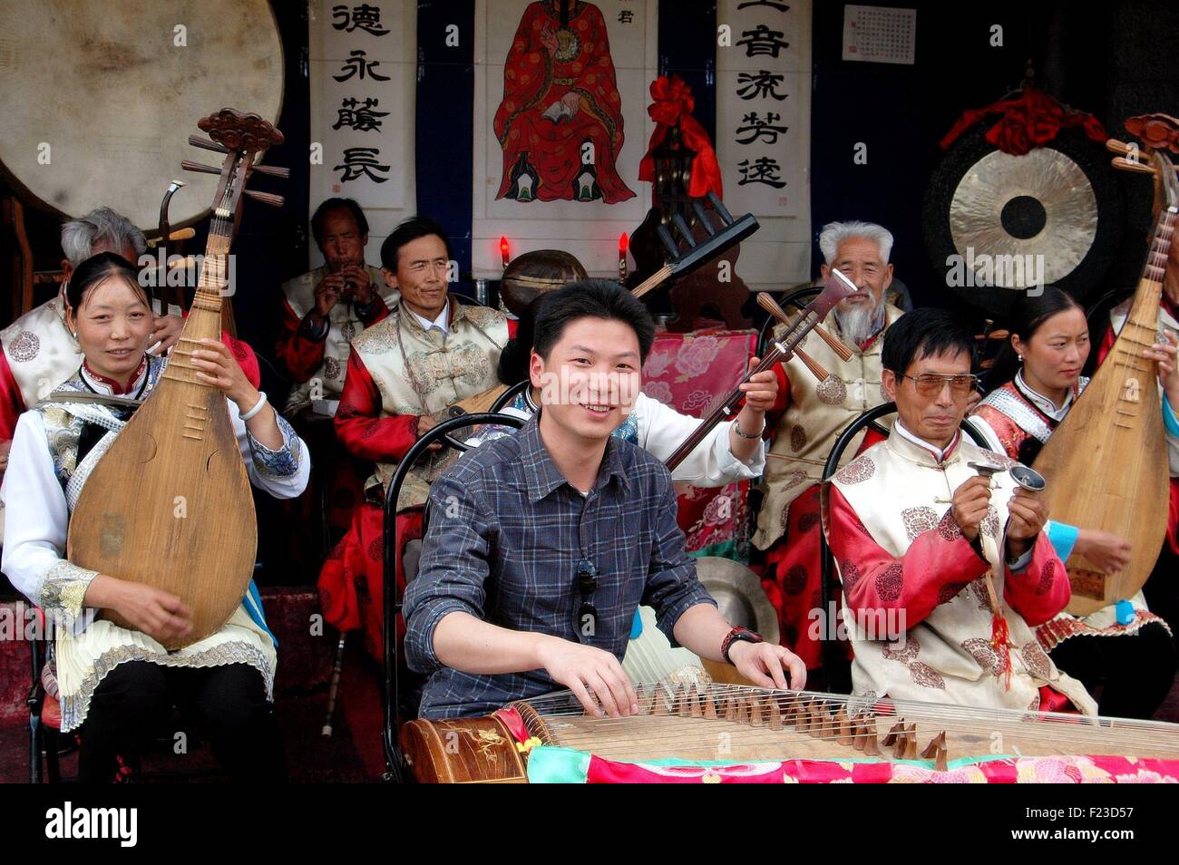 Lijiang, China: Chinesische Jugend spielen eine Zither, begleitet von einer Gruppe von Musikern in einer konzertanten Aufführung Stockfoto