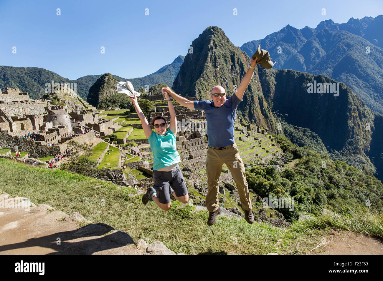 Peru, springen, amerikanische Rucksacktouristen um Ankunft in Machu Picchu mit Huayna Picchu im Hintergrund zu feiern Stockfoto