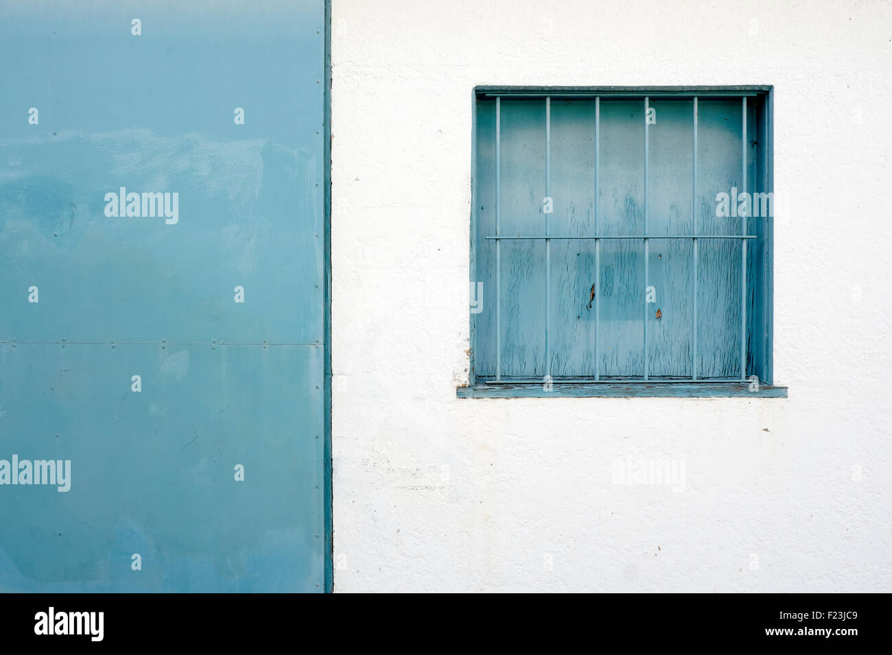 Blaues Quadrat Gitterfenster gegen eine weiße Wand Stockfoto