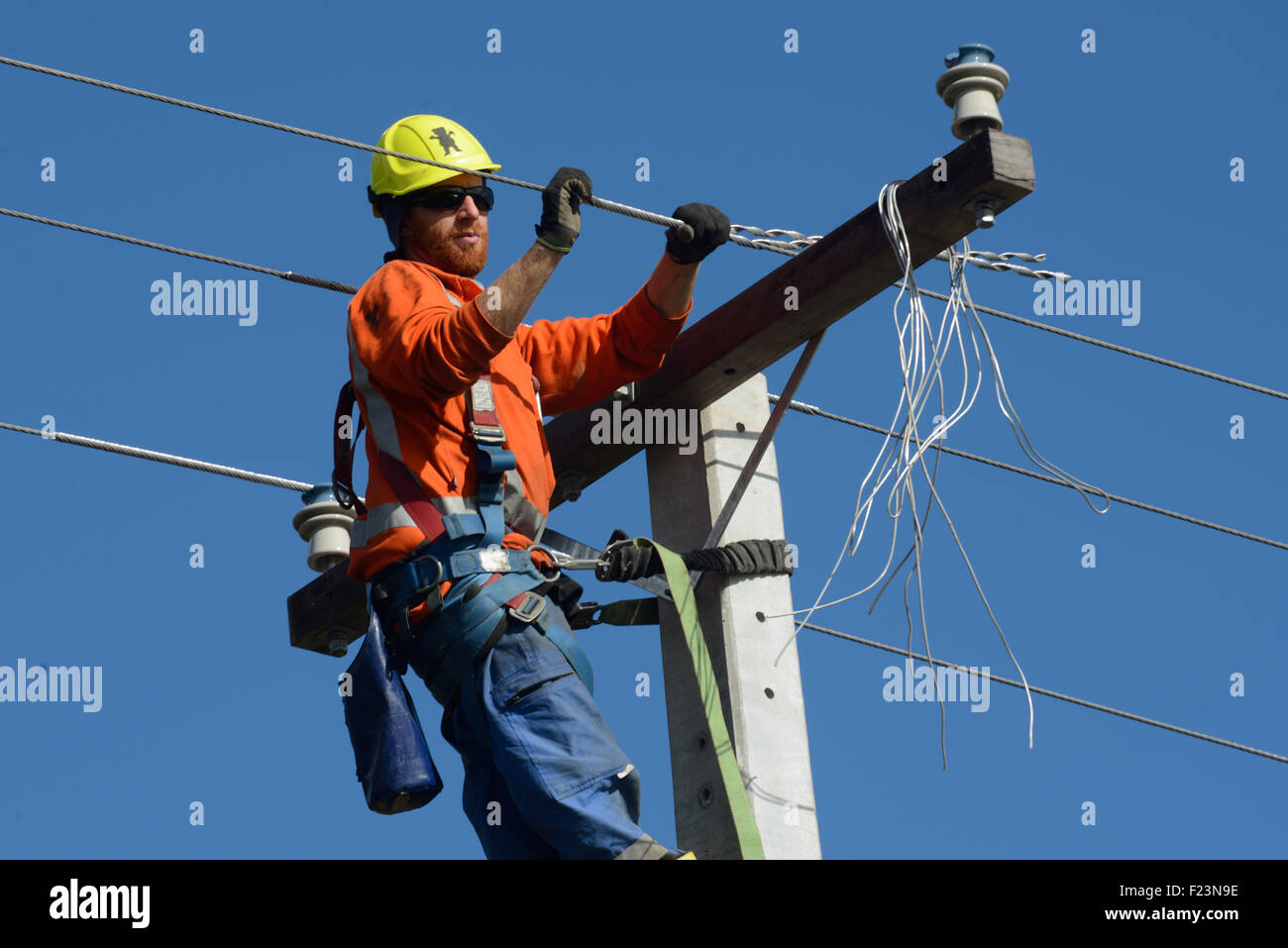 GREYMOUTH, Neuseeland, 5. August 2015: Ein Linienrichter Drähte oben ein Netz Stromversorgungskabel auf einen neuen Pfosten Stockfoto