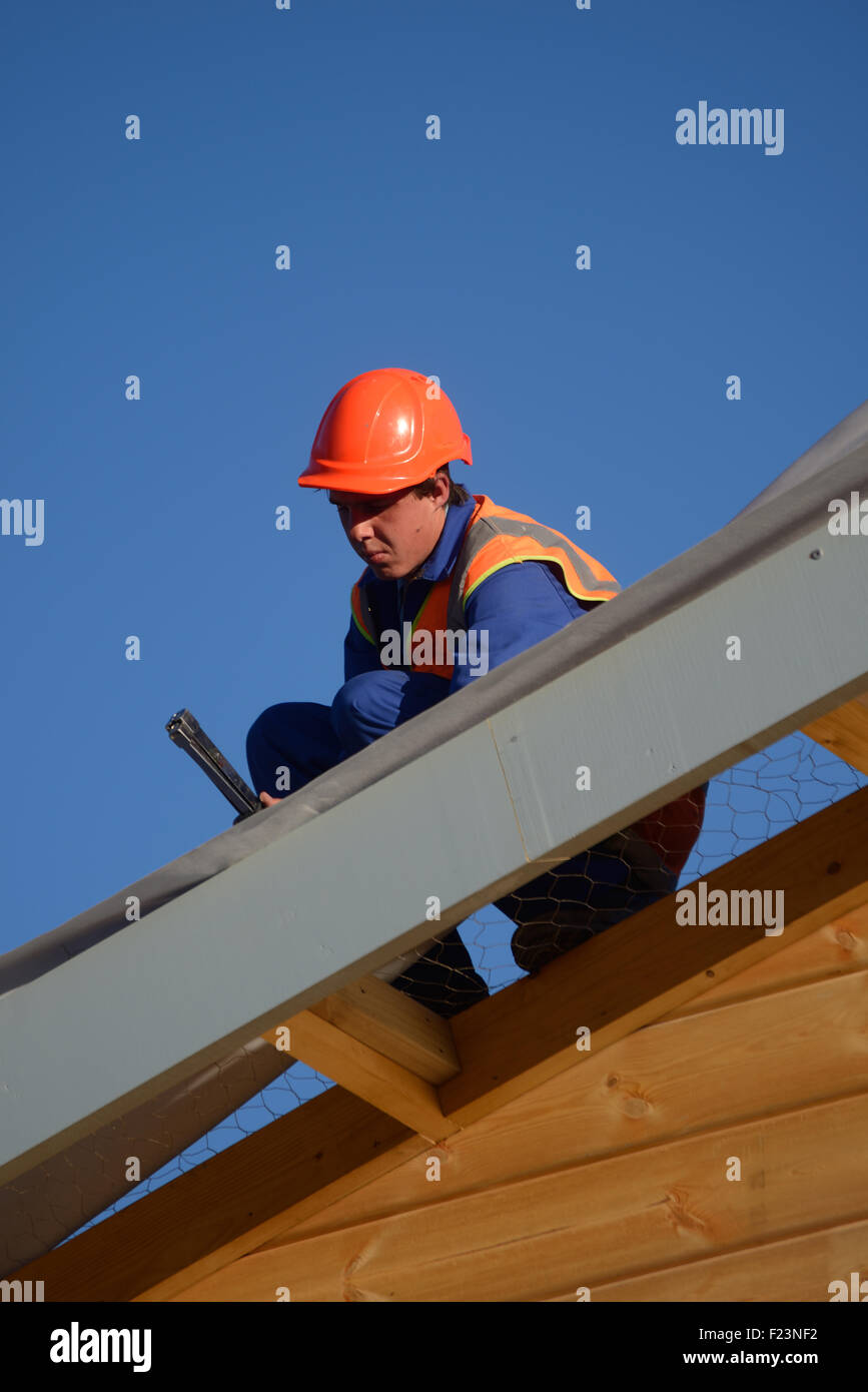 Ein Bauherr sichert wasserdicht Futter Papier auf das Dach eines großen Geschäftshauses, bevor das Eisen weiter geht Stockfoto