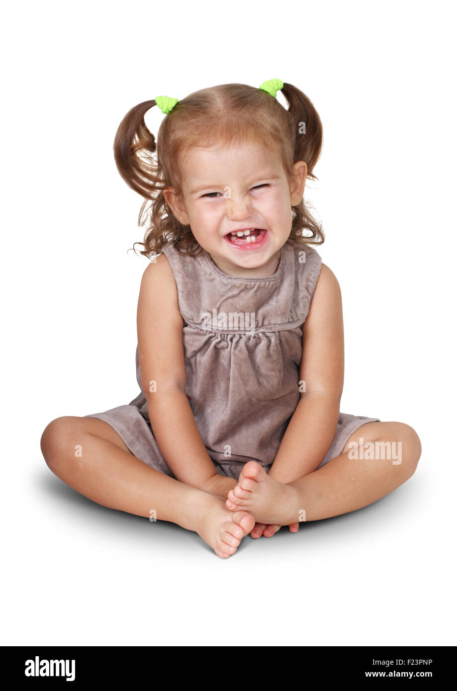 Sitzendes böse Kind Mädchen grinsend isoliert auf weiss Stockfoto