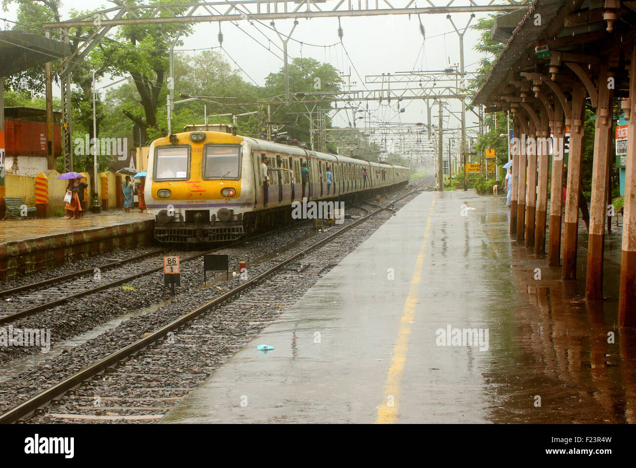 Ein indische lokale Zug fährt einen ländlichen Bahnhof während schweren Monsun-Regen-Saison Stockfoto