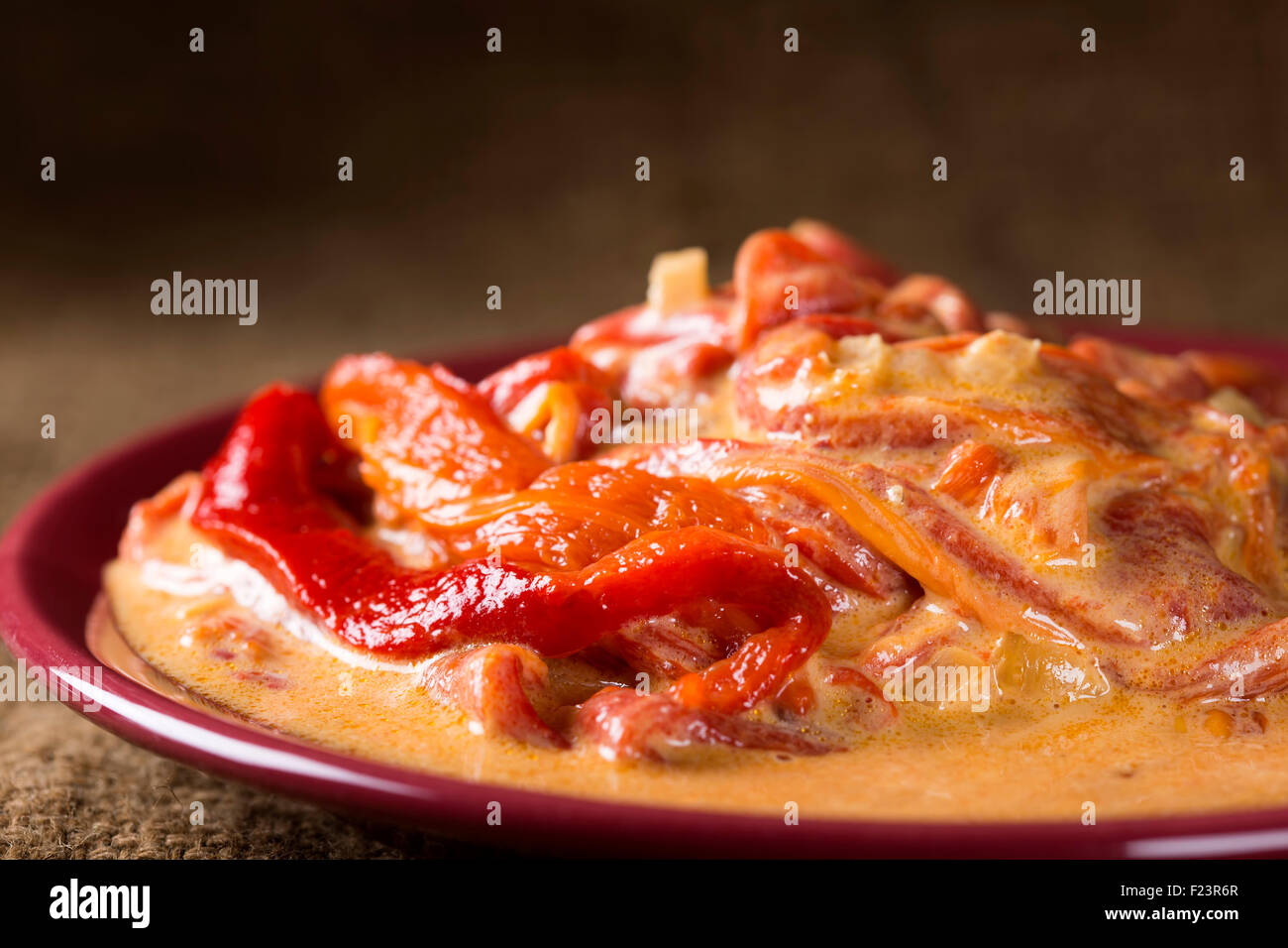 Essen gebratene Paprika mit Sahne auf einem roten Teller Stockfoto